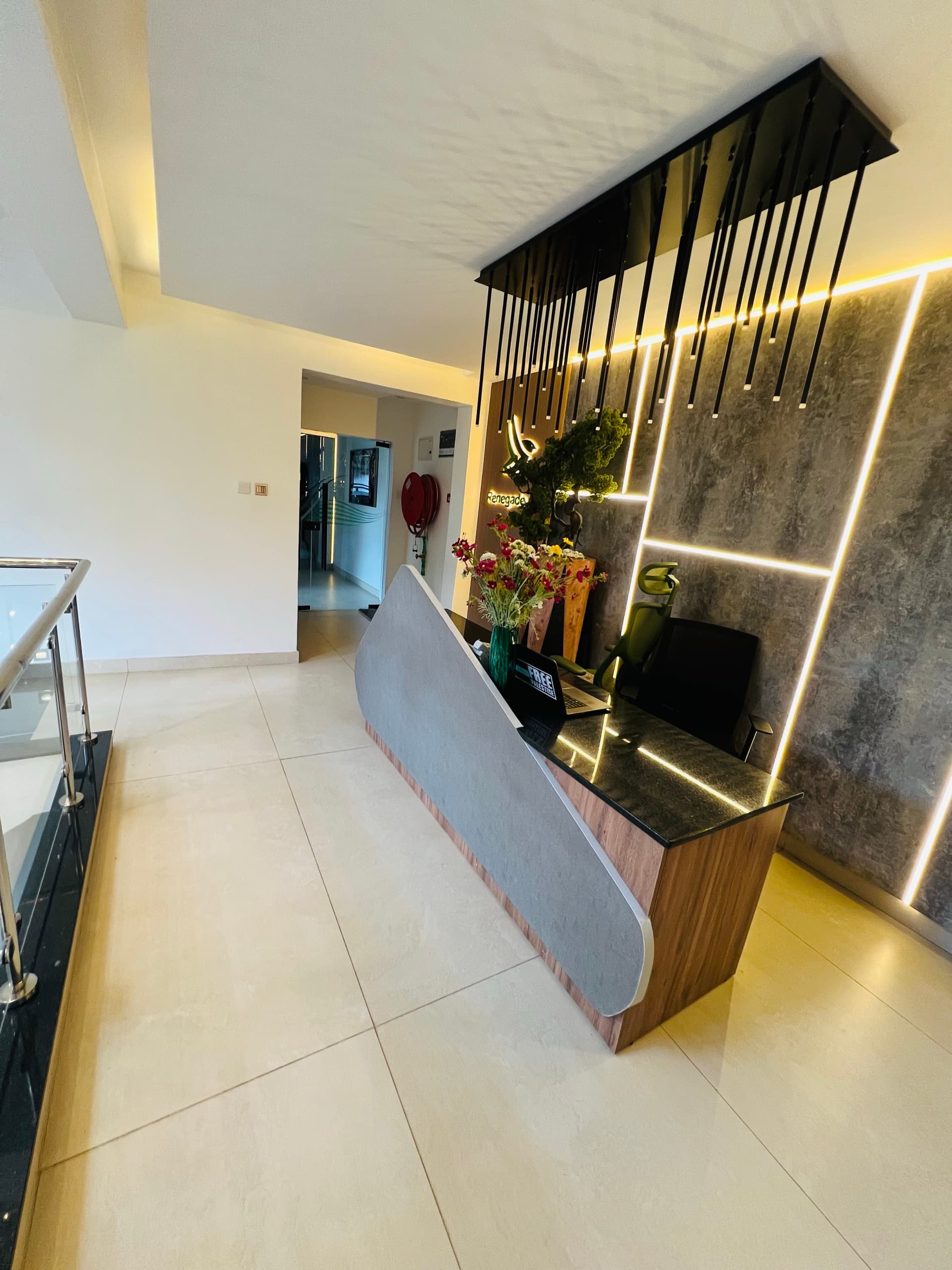 Reception seen from the staircase landing — walnut feature wall and cascading pendant lights